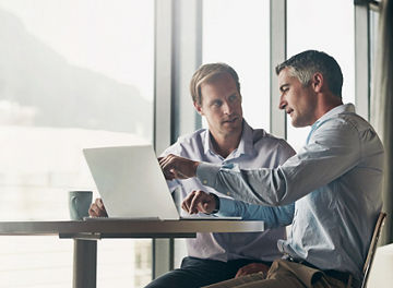 Business, men and discussion with laptop at office for advice, consultation and meeting on investment opportunities. Corporate, people and employees on website with report or feedback on share value.