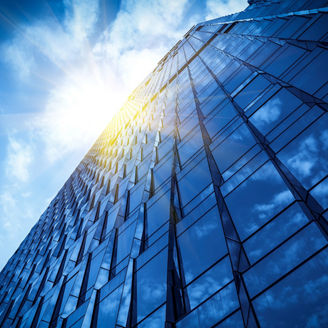 高層ビルのガラス壁面に反射する太陽の光