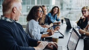 Multi-ethnic business people smiling during a meeting in conference room. Team of professionals having meeting in boardroom.