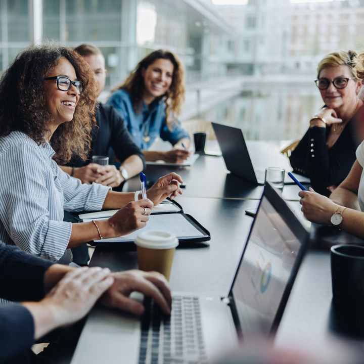 Multi-ethnic business people smiling during a meeting in conference room. Team of professionals having meeting in boardroom.