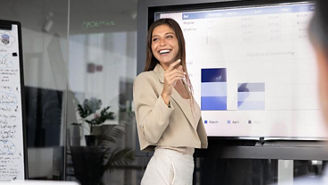 A professional presenting business performance charts on a large screen in a modern meeting room.