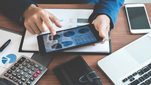 Businessman hands using text information on digital tablet to analyze financial statistical chart data and calculate cost of investment project.