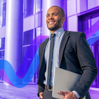 Homem sorridente de fato a sair de um edifício com um portátil na mão