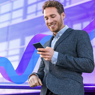 Businessman in a corporate environment looking at his mobile phone whilst smiling.