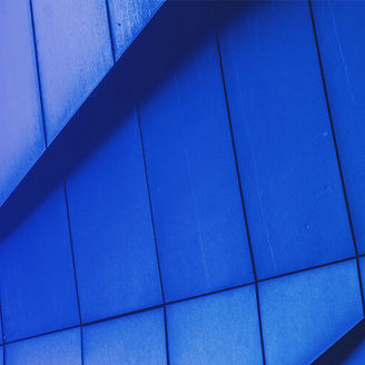 Fachada moderna de edifício com painéis azuis em ângulos geométricos.