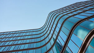 A modern glass business center building with a clear blue sky in the background