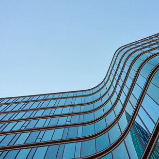 A modern glass business center building with a clear blue sky in the background