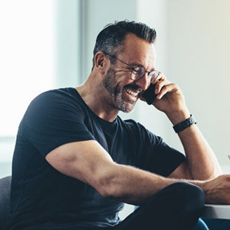 Smiling man at work talking on cell phone and working on his digital tablet. Cheerful businessman working in office.
