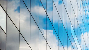 A reflection of clouds and sky in a mirrored glass building.