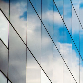 A reflection of clouds and sky in a mirrored glass building.