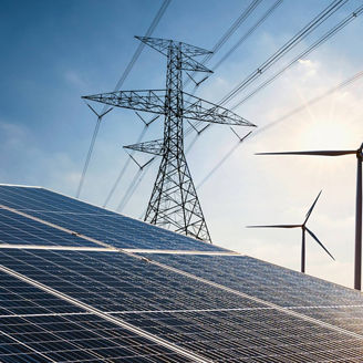Solar panels and electricity pylons with wind turbines in the background under a blue sky