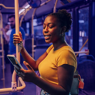An attractive african american woman using a smartphone while riding a bus in the night. Young beautiful black woman using public transportation. Illuminated by the city light.; Shutterstock ID 2191833297; purchase_order: marketing advisory assurance; job: anne rouschop; client: ai-campagne