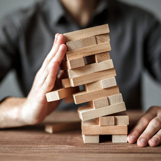 Businessman holds the model of business, made from wood blocks. Alternative risk concept, business plan and business strategy. Insurance concept.