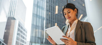 Frau mit Tablet vor Gebäuden