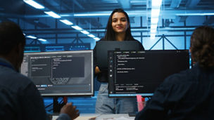 Portrait of smiling Indian manager in server room managing team of engineers looking for equipment misconfigurations. Happy team leader coordinating employees checking data center bottlenecks