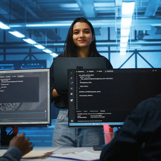 Portrait of smiling Indian manager in server room managing team of engineers looking for equipment misconfigurations. Happy team leader coordinating employees checking data center bottlenecks