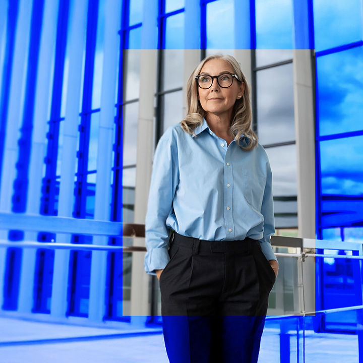Voksen kvinne står foran et kontorbygg og ser ettertenksomt utover. 