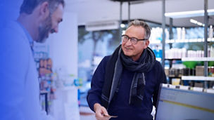 A senior man is making a retail transaction in a chemist