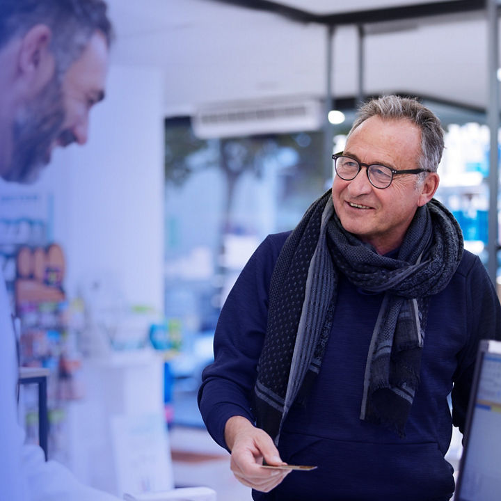 A senior man is making a retail transaction in a chemist