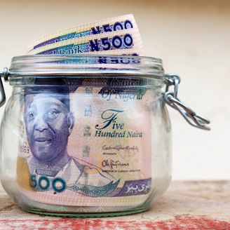 Saved five hundred naira notes savings jar with some notes sticking out of the top of the open jar for banking, insurance, savings and investment concept