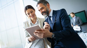 Happy business colleagues in modern office using tablet
