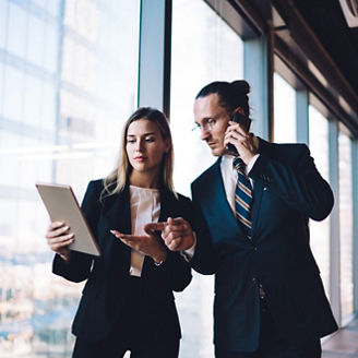 Caucasian boss reading financial news on modern touch pad while communicating with corporate investor via cellphone, formally dressed colleagues using technology with 4g internet in office interior