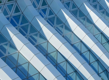 Modern architecture. Abstract pattern of shadows and light on curved diagonal lines of contemporary facade.Fragment of the facade of glass building.