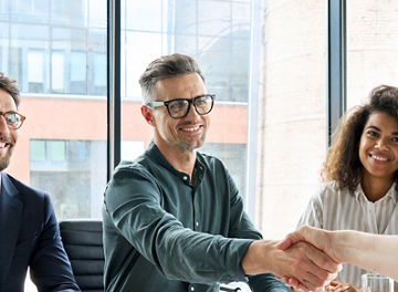 Happy businessman and businesswoman shaking hands at group board meeting. Professional business executive leaders making handshake agreement successful company trade partnership handshake concept.