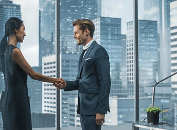 Female and Male Business Partners Meet in Office, Shake Hands. Corporate CEO and Finance Manager Have Meeting in City Office. Businesspeople Came to Discuss Real Estate Purchase and Marketing Project.