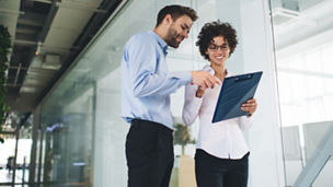 Bottom view of businessman point with finger on clipboard in hand of his female colleague. Business cooperation and teamwork. Young caucasian millennial colleagues in office. Modern successful people
