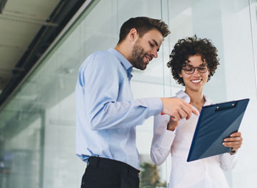 Bottom view of businessman point with finger on clipboard in hand of his female colleague. Business cooperation and teamwork. Young caucasian millennial colleagues in office. Modern successful people