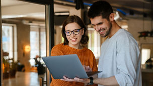 White colleagues discussing project while working with laptop in office indoors