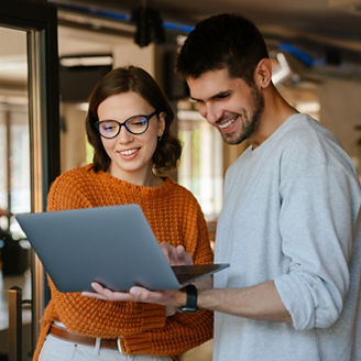 White colleagues discussing project while working with laptop in office indoors
