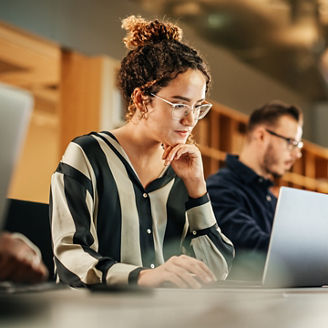 Portrait of Enthusiastic Hispanic Young Woman Working on Computer in a Modern Bright Office. Confident Human Resources Agent Smiling Happily While Collaborating Online with Colleagues.