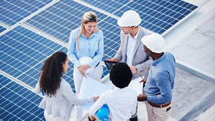 Solar and renewable energy, blueprint or engineering team on roof building electricity technology for sustainability. Collaboration, top view or black man talking or planning a project with people