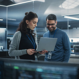 Portrait of Two Happy Female and Male Engineers Using Laptop Computer to Analyze and Discuss How to Proceed with the Artificial Intelligence Software. Casually Chatting in High Tech Research Office
