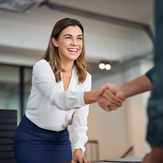 Happy mid aged business woman manager handshaking greeting client in office. Smiling female executive making successful deal with partner shaking hand at work standing at meeting table.