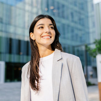 Portrait of young successful entrepreneur woman standing over modern company office building. Startup, vision and female empowerment