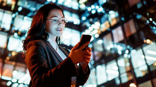 Young businesswoman using phone in the city in the evening.