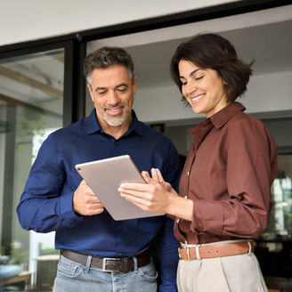 Professional business people, two happy busy business man and woman executives partners team working together standing in office using digital tablet in corporate cooperation on company project.