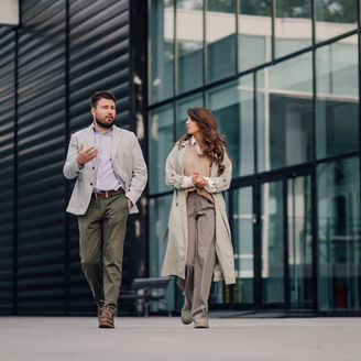 Two business partners discussing work and success while walking outside a modern office building in the city