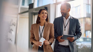 Happy business colleagues communicating while walking through an office building. Copy space.