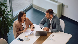 High angle view of happy entrepreneur and her colleague talking during business meeting in the office. Copy space.
