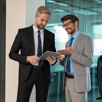 Two business people discussing work together using a tablet in a modern office.