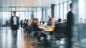 Busy modern office meeting with blurred figures in motion