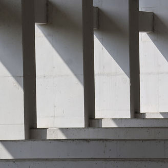Abstract architecture of concrete structure with geometric pattern. Strong light and shadow create stark, minimalist composition with repeating lines and sense of quiet solitude