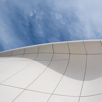 Abstract architectural form with smooth white curves framing sky view