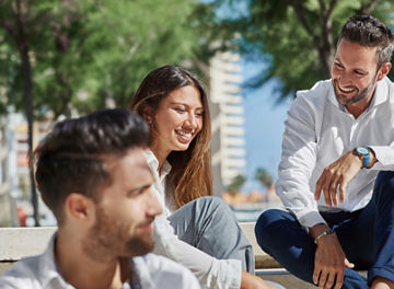 Young happy people sitting together outside laughing