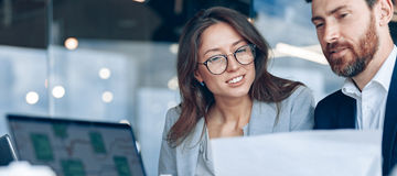 Close up of smiling businessmen discussing documents with graphs and charts in a modern office.