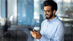 Young successful mature businessman inside the office using the phone, man holding a smartphone online application user, smiling browsing the internet and dialing a call.